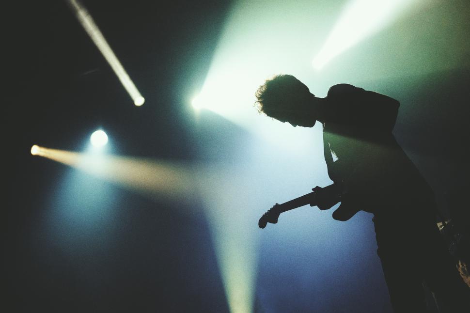 Free Image of A man playing a guitar on a stage 