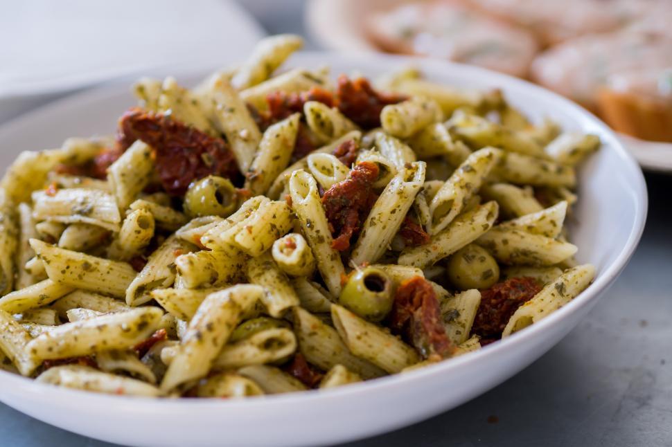 Free Image of A bowl of pasta with pesto sauce and olives 
