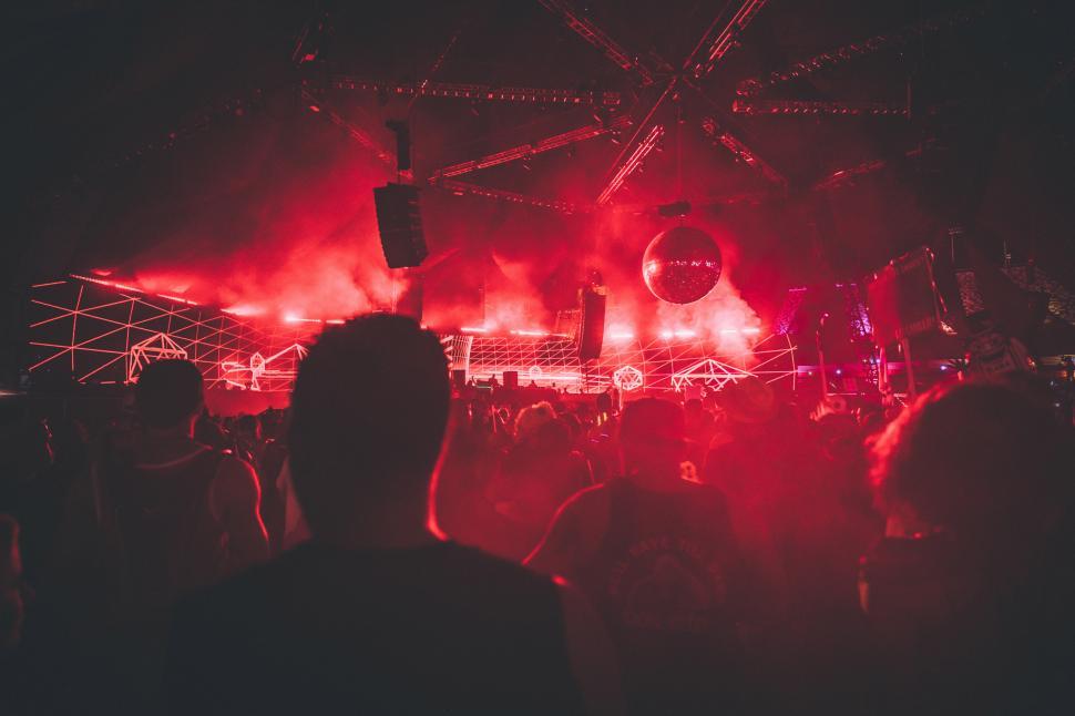 Free Image of A crowd of people in front of a stage with red lights 