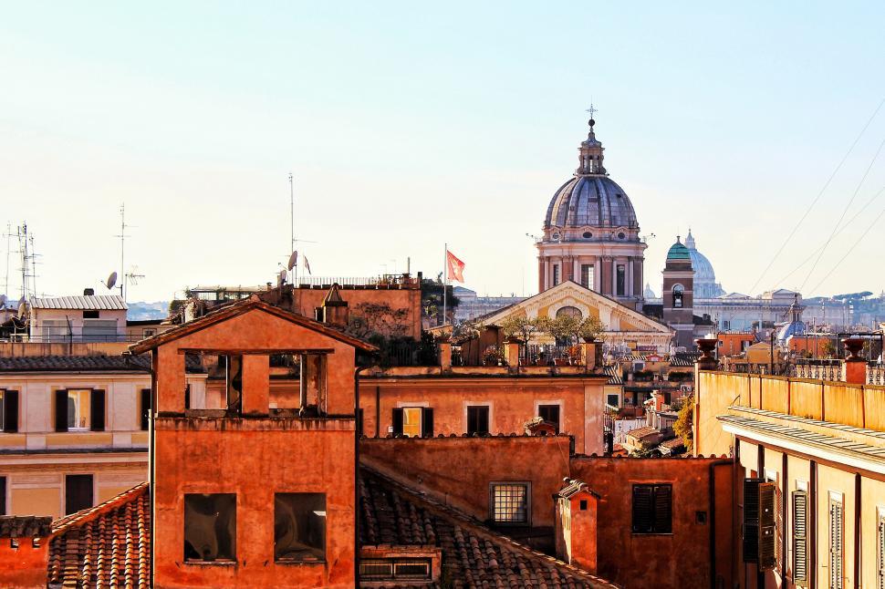 Free Image of A rooftops of buildings with a dome in the background 