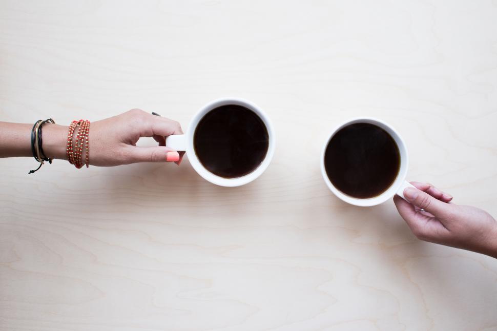 Free Image of A pair of hands holding coffee cups 