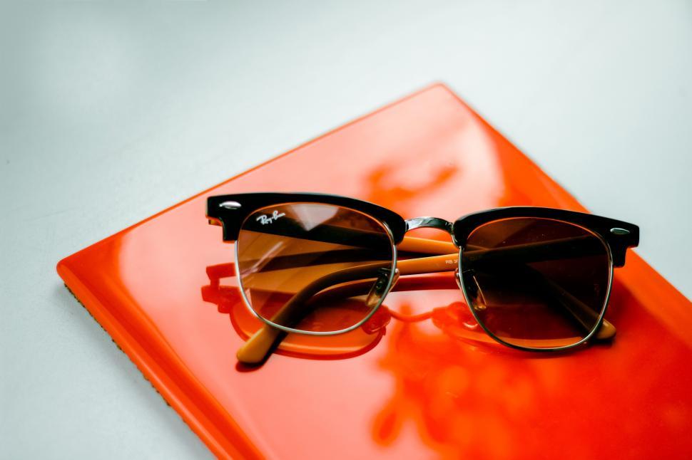 Free Image of A pair of sunglasses on an orange book 