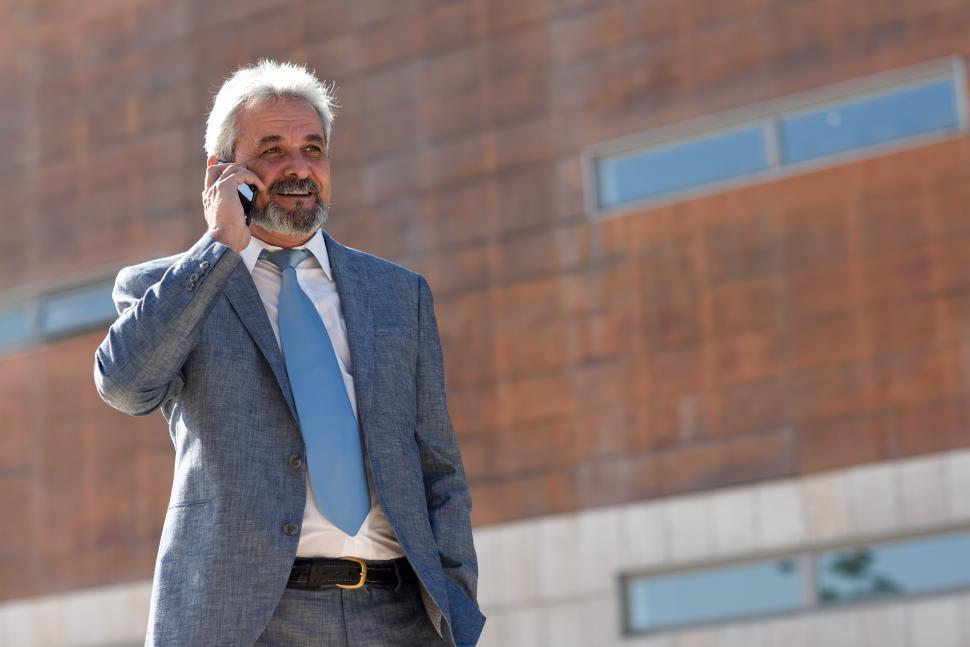 Free Image of Senior businessman with smartphone outside of modern office building. 