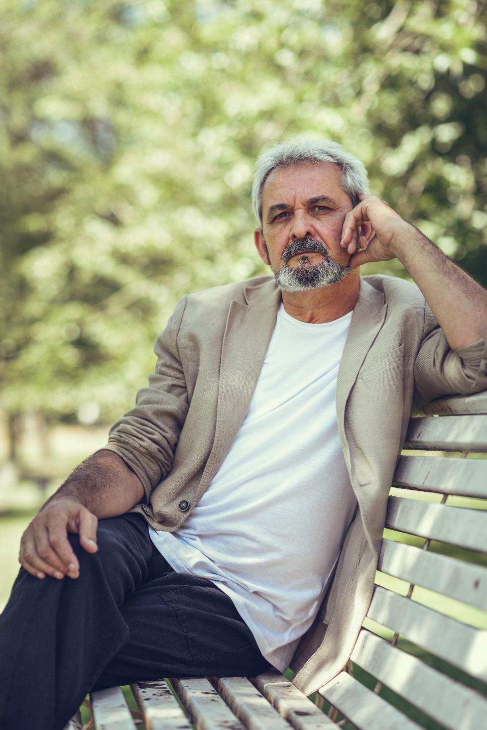 Free Image of Pensive mature man sitting on bench in an urban park looking at camera 
