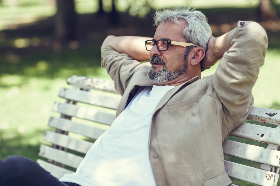 Free Image of Pensive mature man sitting on bench in an urban park. 
