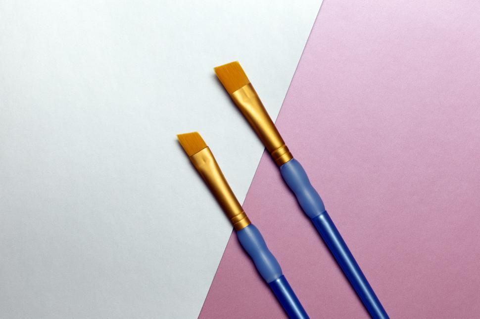 Free Image of A pair of paint brushes on a white and purple surface 
