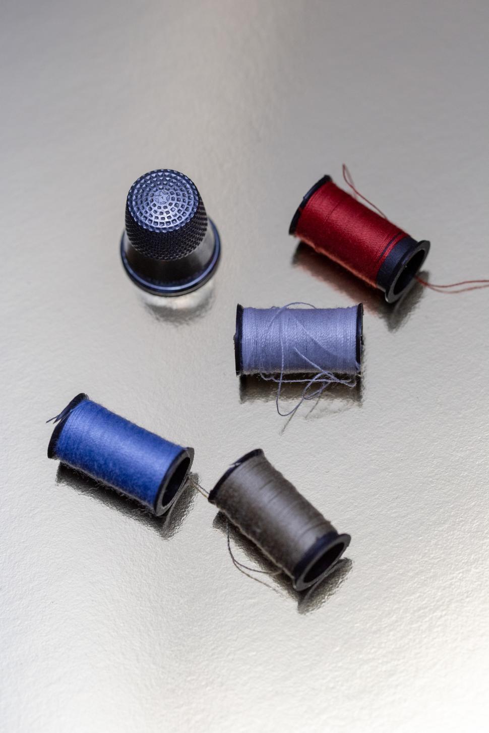 Free Image of A group of spools of thread and thimble 