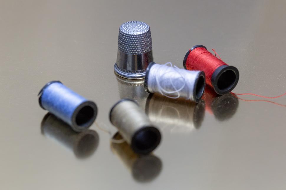 Free Image of A group of spools of thread and a thimble 