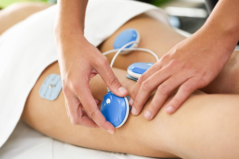 Free Image of Physiotherapist applying electro stimulation in physical therapy to a young woman leg. 