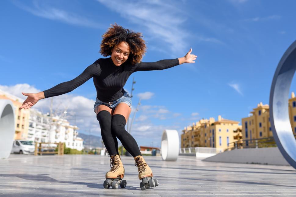 Free Image of Black woman on roller skates riding outdoors on urban street 