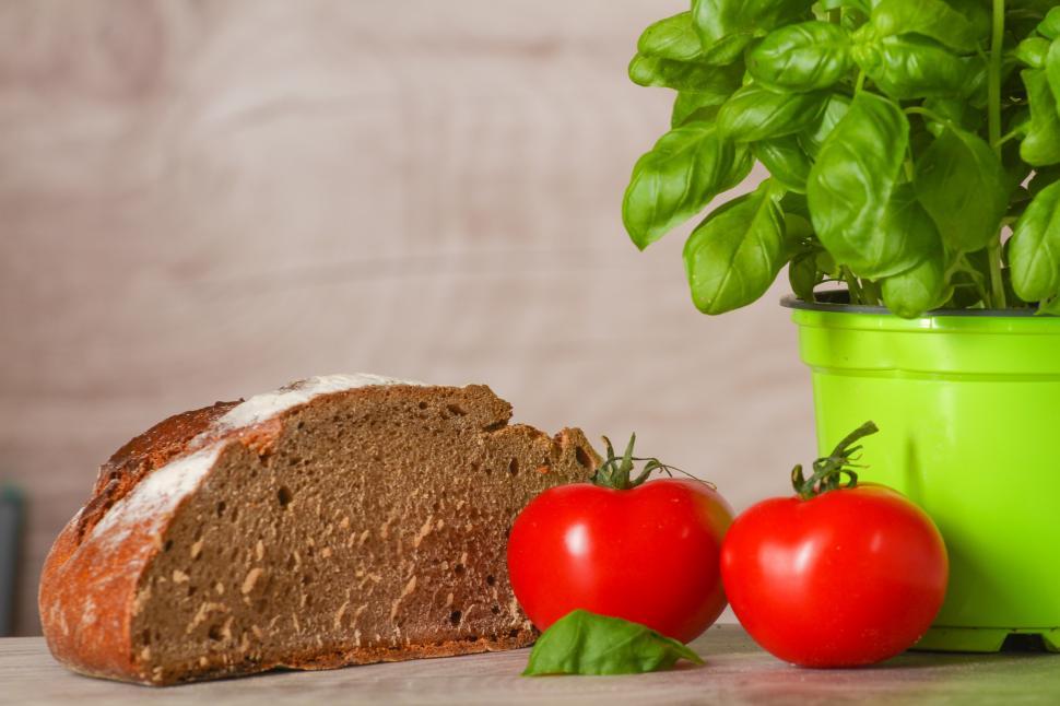 Free Image of A loaf of bread and tomatoes next to a plant 