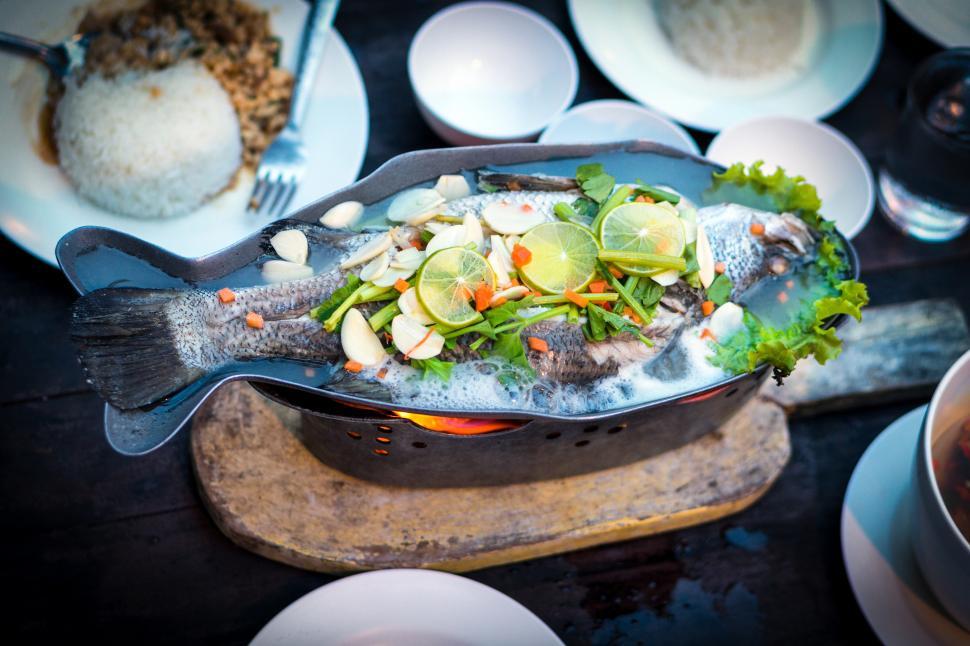 Free Image of A fish with limes and herbs in a pan 