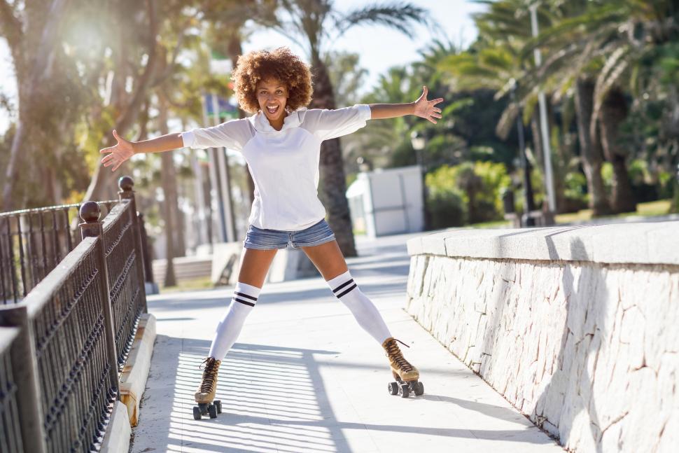 Free Image of Black woman, afro hairstyle, skating near the beach. 