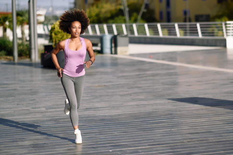 Free Image of Black woman, afro hairstyle, running outdoors in urban road. 