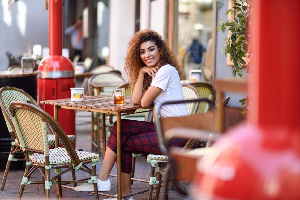 Free Image of Girl in casual clothes drinking a soda in an outdoors bar 