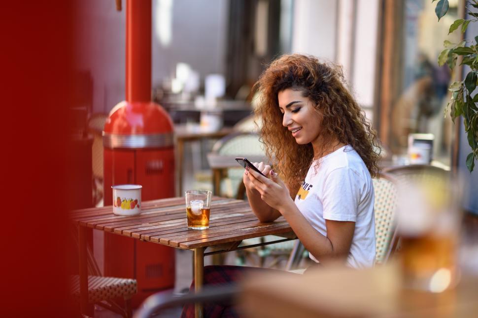 Free Image of Young woman in an urban bar at her smartphone. 