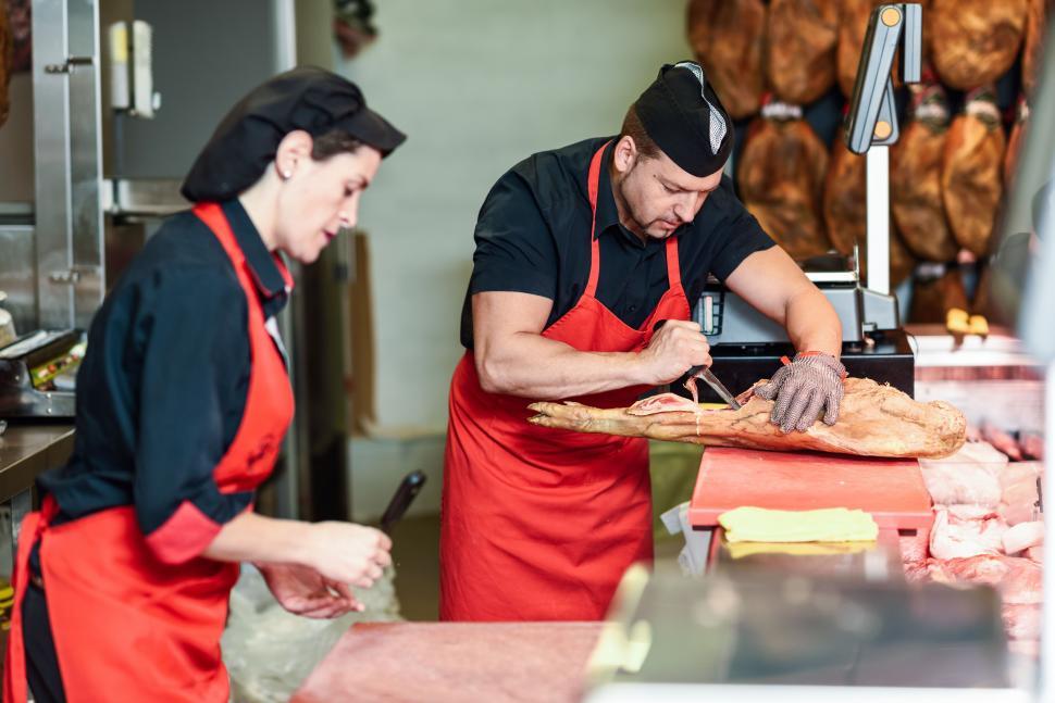 Free Image of Butchers boning a ham in a modern butcher shop 