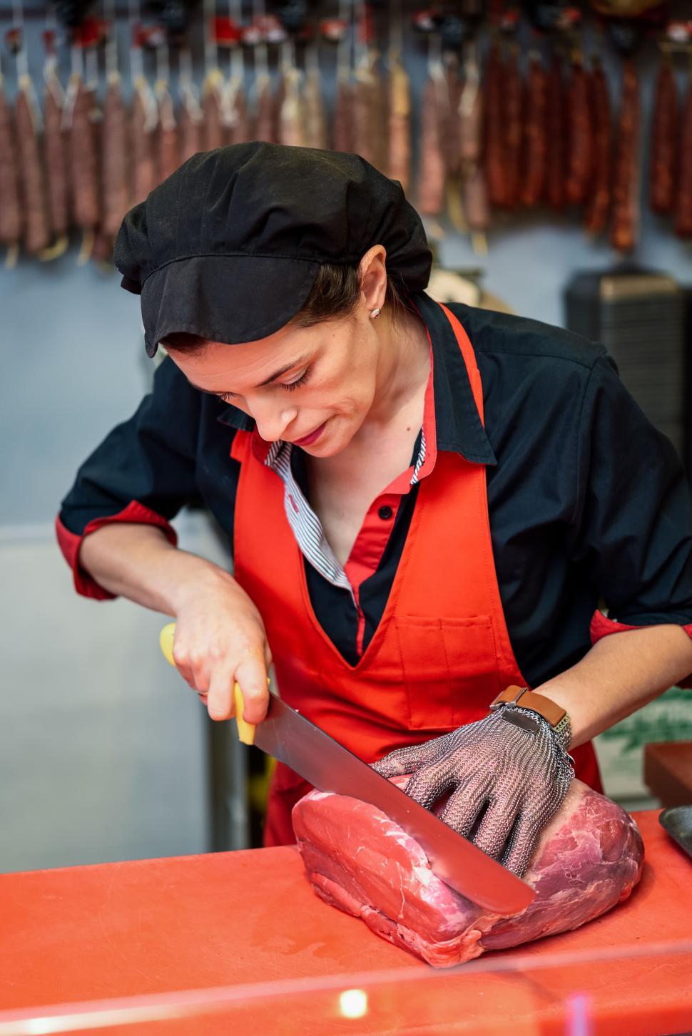 Free Image of Woman cutting fresh meat in a butcher shop with metal safety mesh glove 