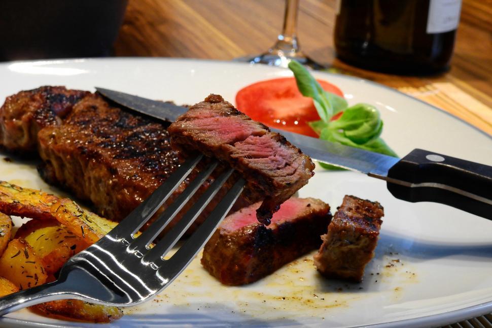 Free Image of A fork and knife on a plate of steak 