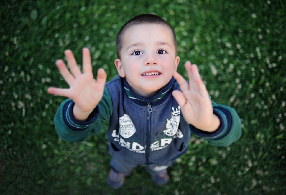 Free Image of A boy standing in the grass with his hands up 