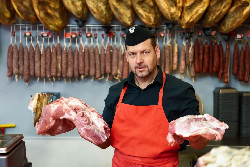 Free Image of Butcher holding meat standing in a butcher shop 