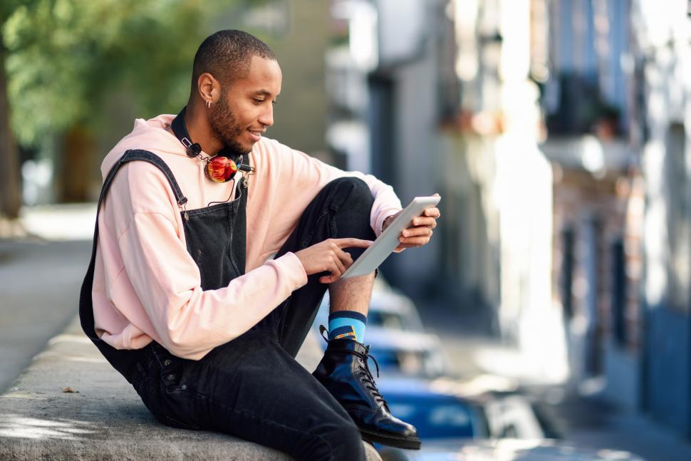 Free Image of Young black man using digital tablet in urban background. 