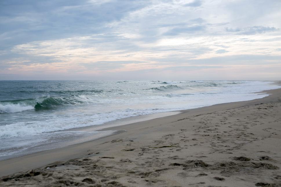 Free Image of A beach with waves crashing on the shore 