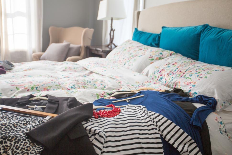 Free Image of Clothes on a bed with a lamp and a flowered bed 
