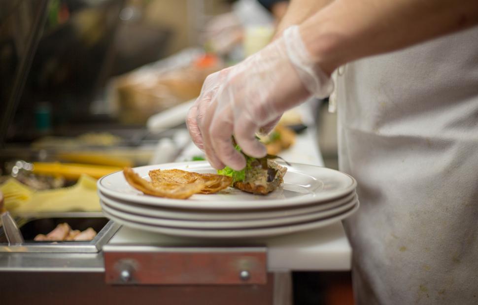Free Image of A person wearing gloves putting food on a plate 