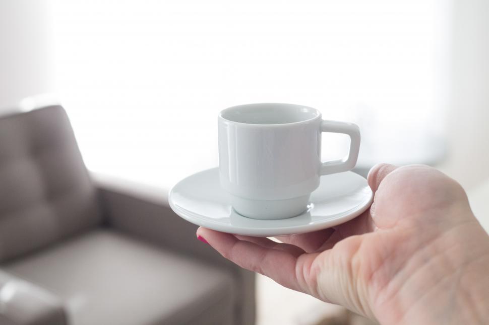 Free Image of A hand holding a small white cup and saucer 