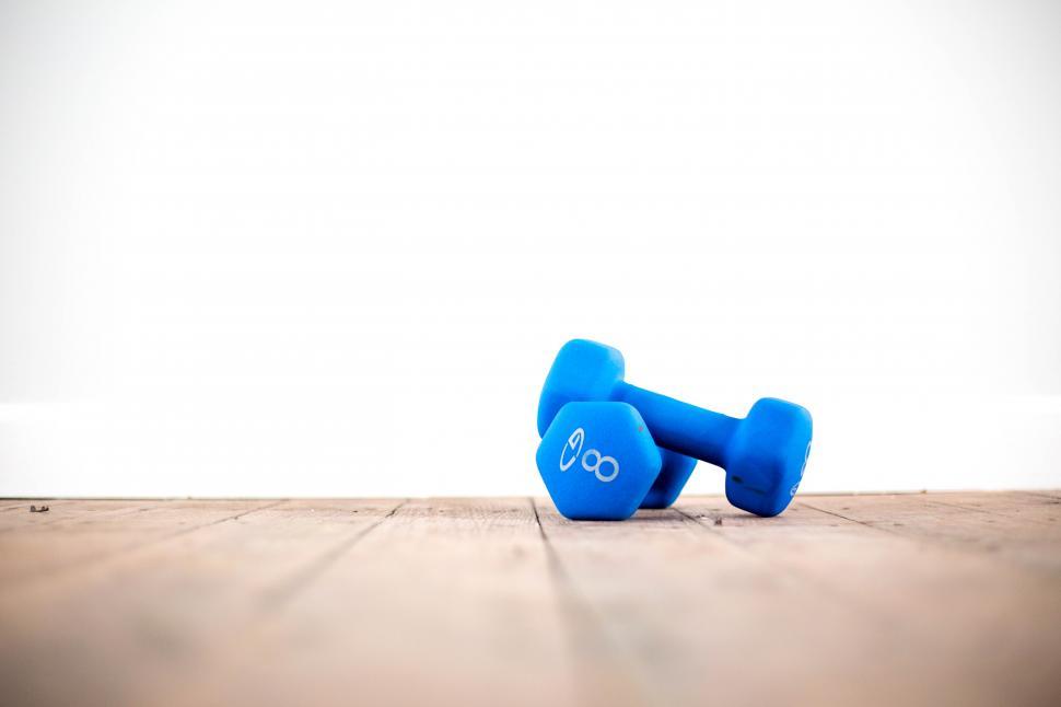 Free Image of A pair of blue dumbbells on a wooden surface 