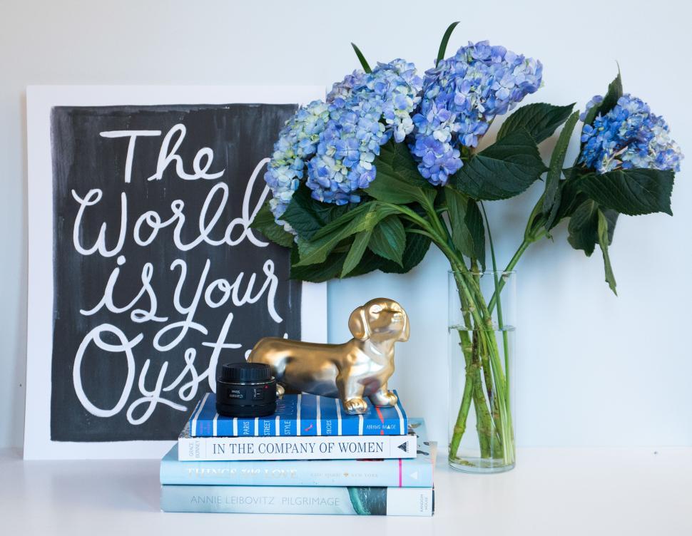 Free Image of A vase of flowers next to a book and a statue of a dog 