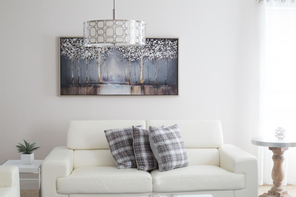 Free Image of A white couch with pillows and a lamp from the ceiling 