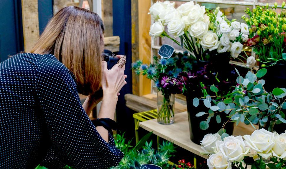 Free Image of A woman taking a picture of flowers 