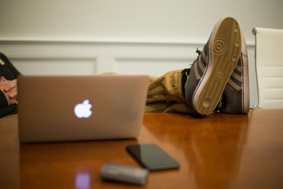 Free Image of A person s feet with a laptop and a phone on a table 