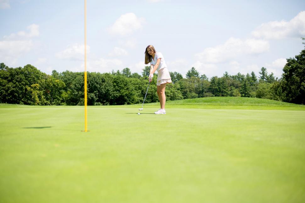 Free Image of A woman playing golf on a green field 