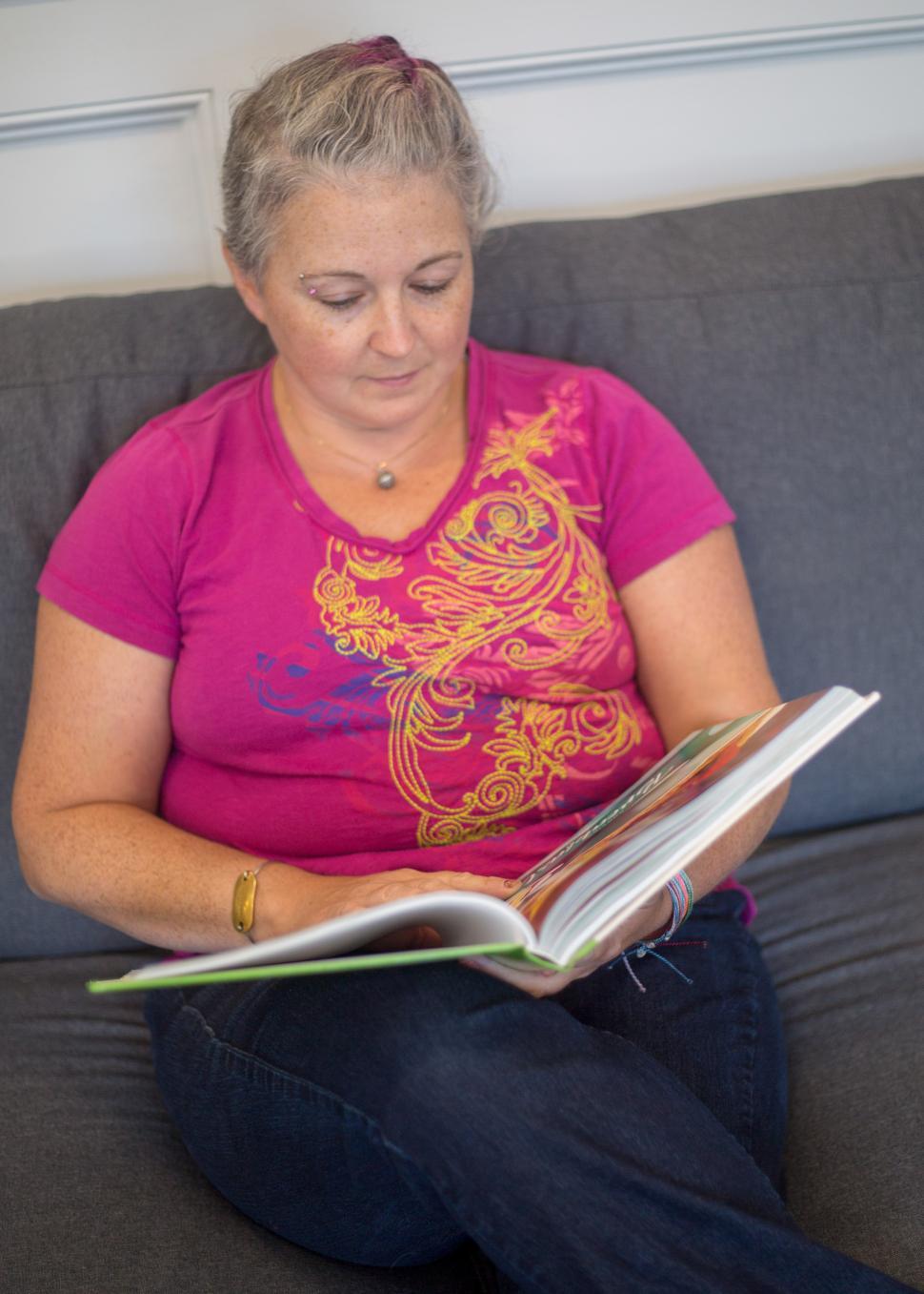Free Image of A woman sitting on a couch reading a book 