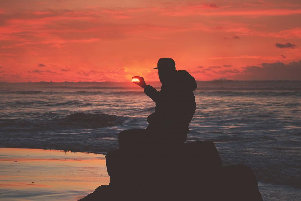 Free Image of A silhouette of a man holding a ball in front of a sunset 