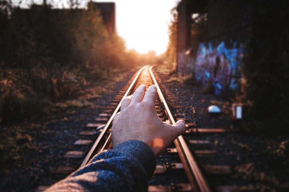 Free Image of A hand reaching out to the side of a train track 
