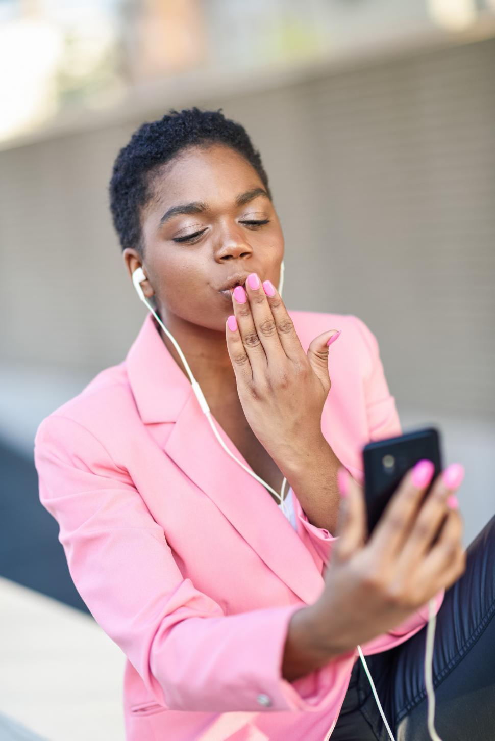 Free Image of Black businesswoman sitting outdoors speaking via videoconference with her smart phone. 