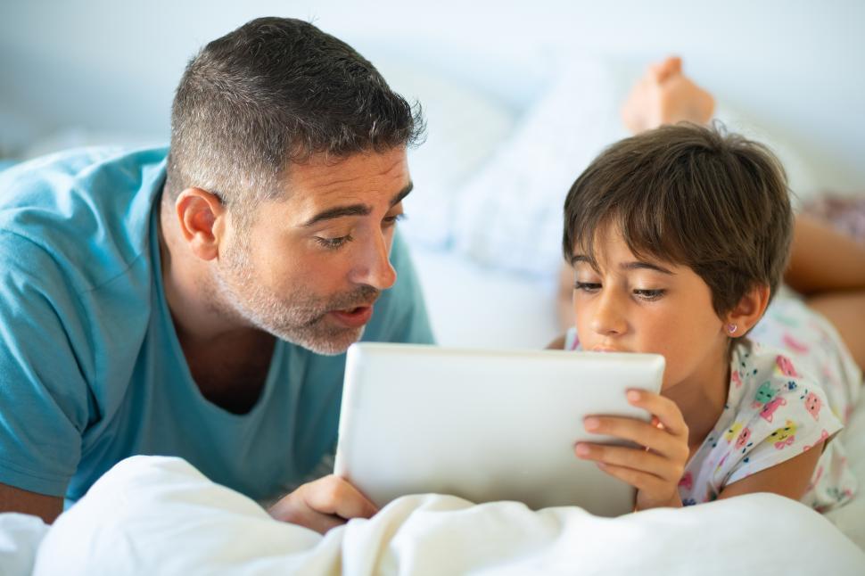 Free Image of Middle-age father with her eight years daughter using digital tablet in bedroom. 