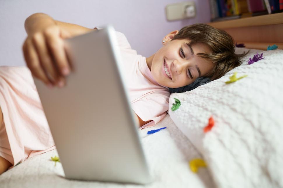 Free Image of Cute girl using a tablet computer in her bedroom 