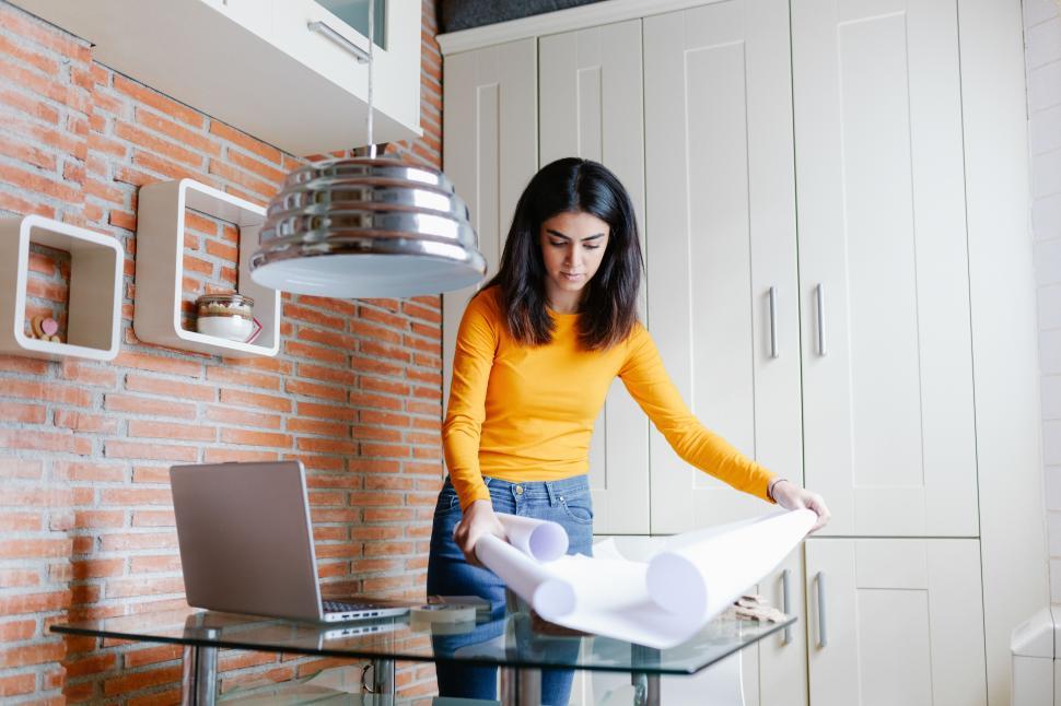 Free Image of Female architect working at home with a laptop and blueprints 