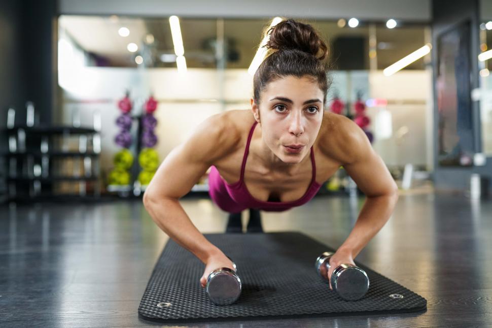 Free Image of Woman doing push-ups exercise with dumbbell in a fitness workout 