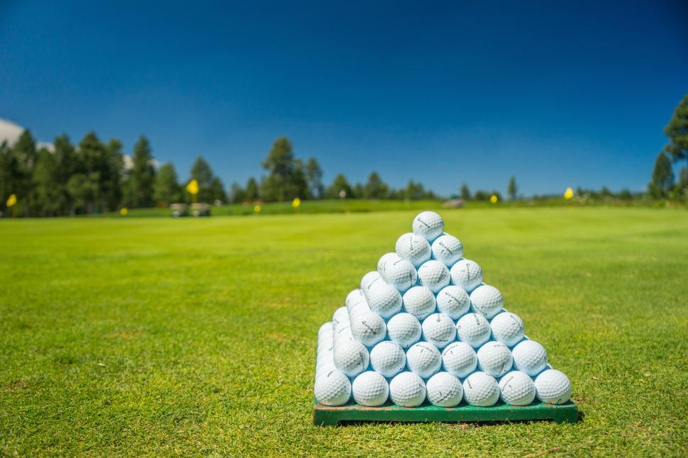 Free Image of A pyramid of golf balls on a green field 