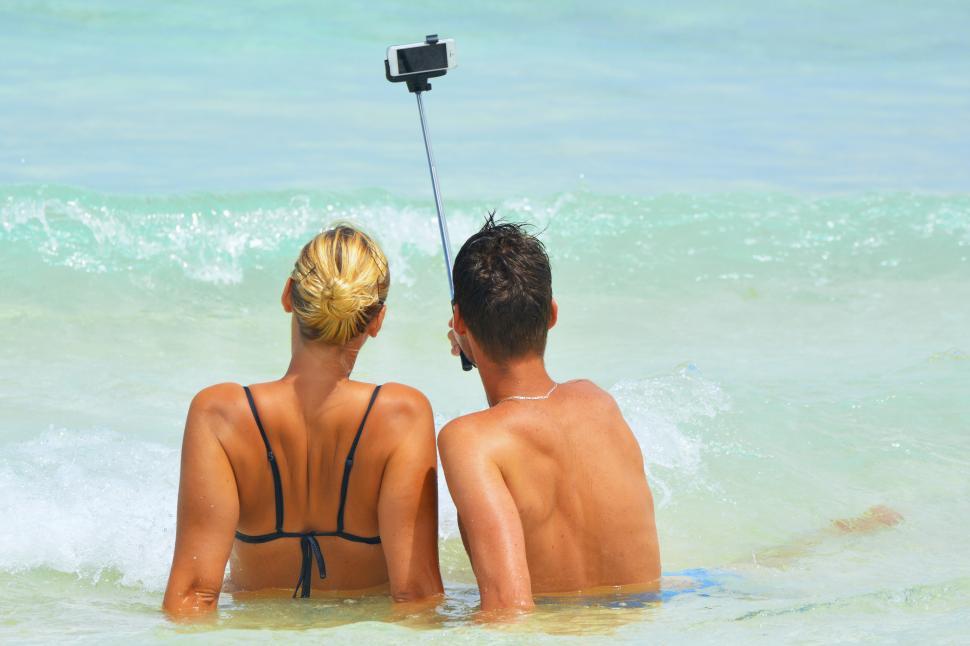 Free Image of A man and woman sitting in the water taking a selfie 