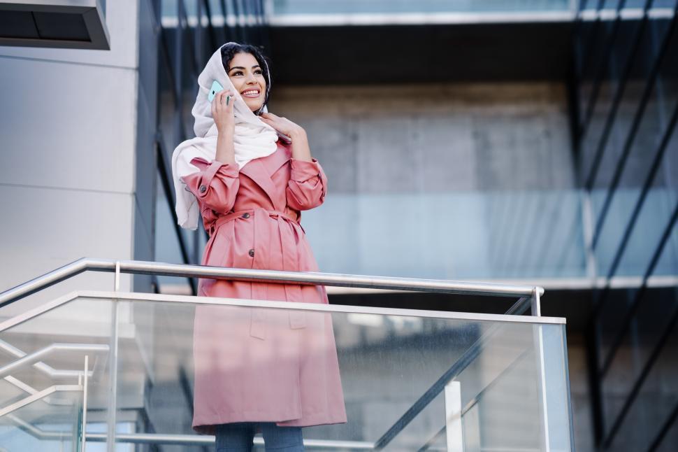 Free Image of Young Muslim woman wearing hijab using her smartphone. 