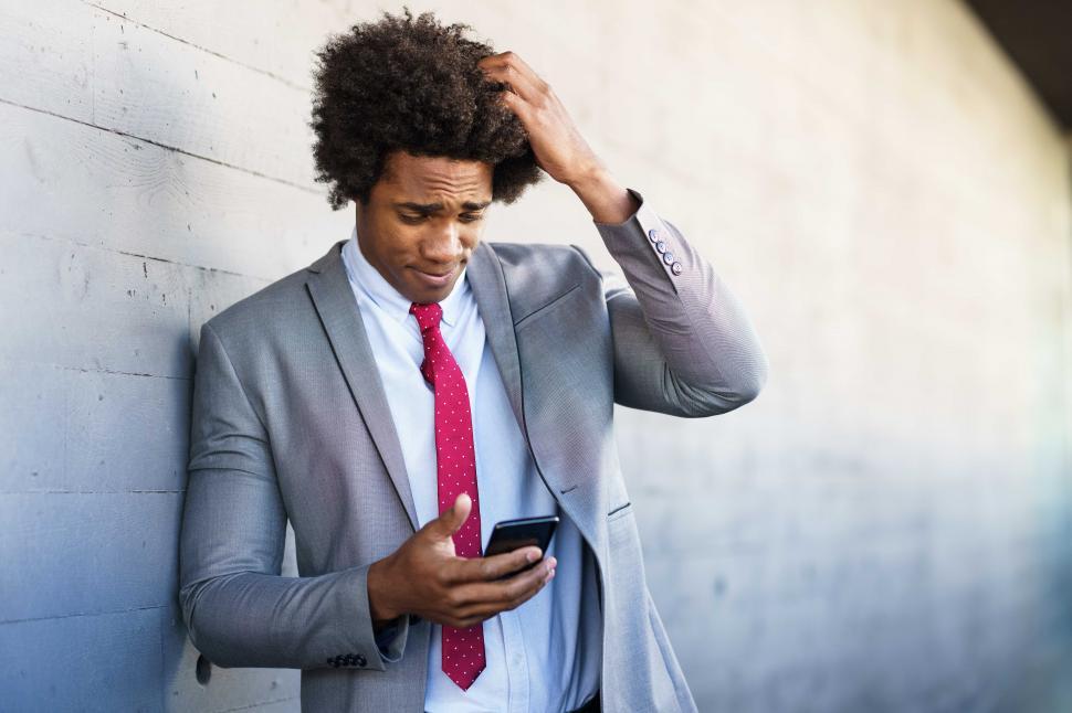 Free Image of Worried Black Businessman using his smartphone outdoors. 