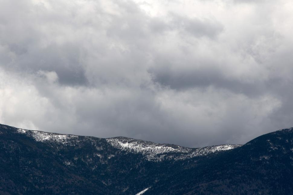 Free Image of A snowy mountain tops with clouds in the sky 