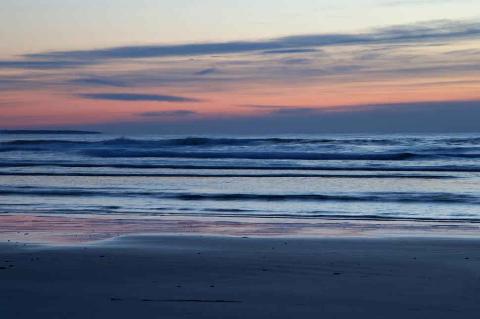 Free Image of A beach with waves and a sunset 
